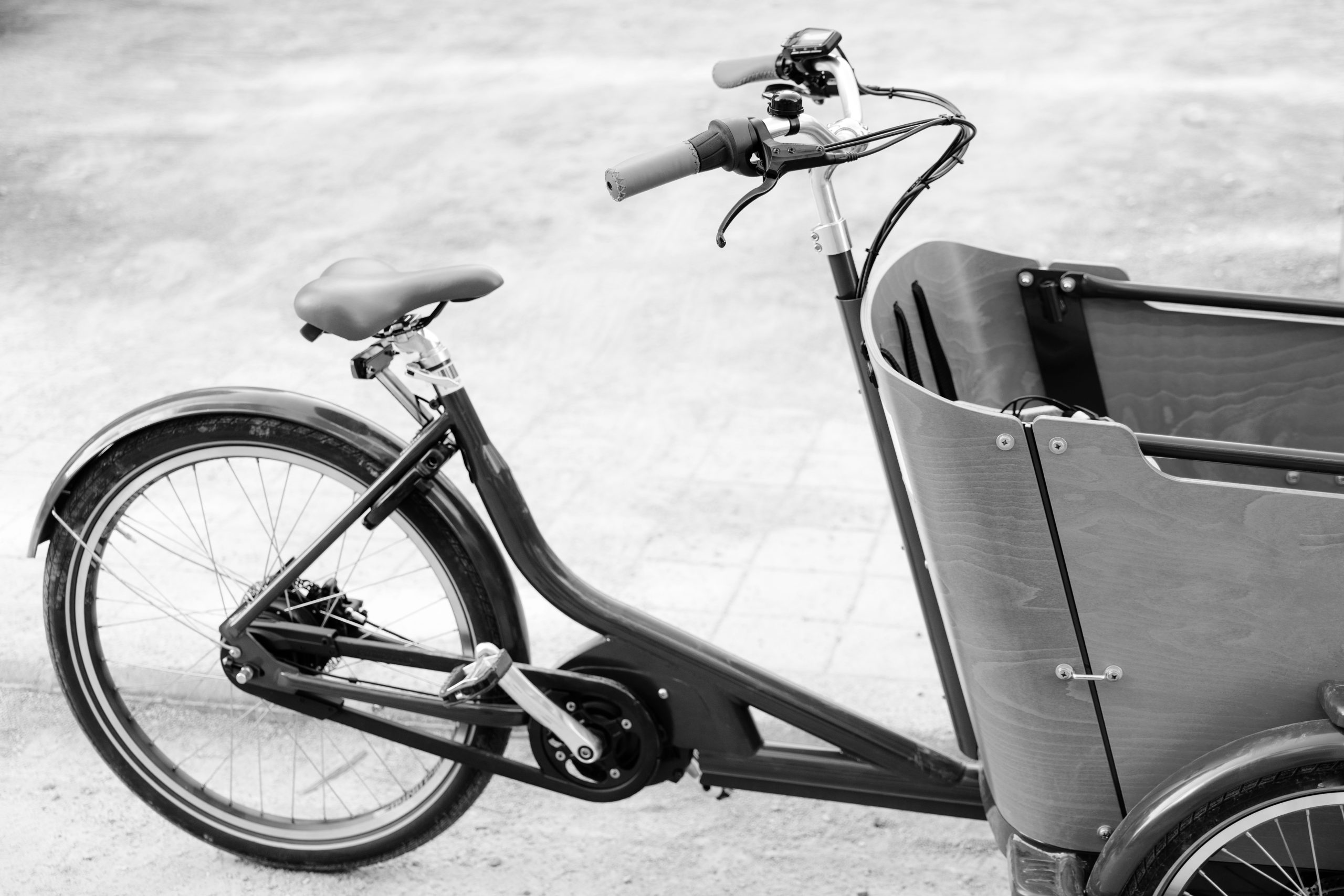 vous pouvez voir un vélo cargo électrique, garé. La photo est en noir et blanc.
